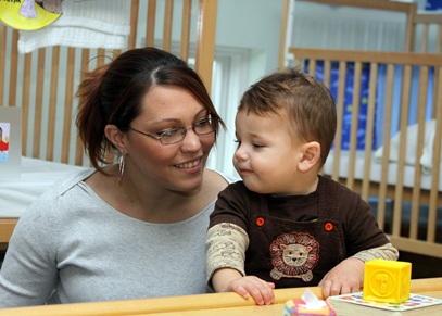 Woman and toddler playing with toys in classroom